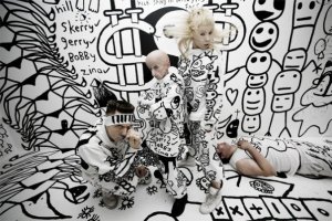 Members of Die Antwoord pose in front of black and white graffiti