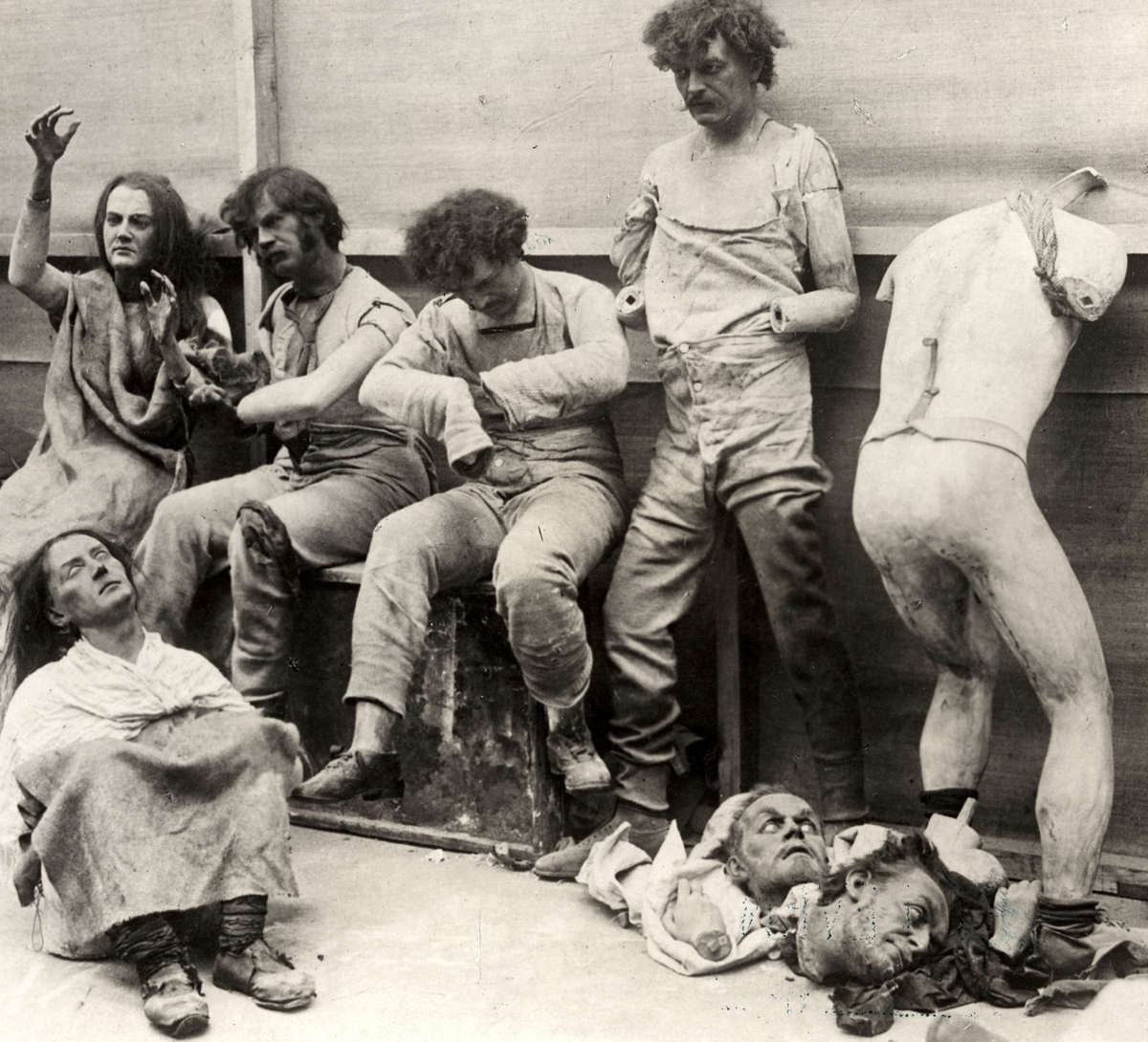 Photograph of six wax figures and broken body parts damaged from fire.