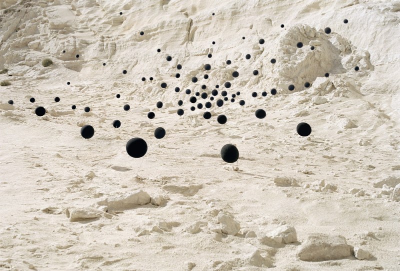 Photograph by Andrea Galvani of black balloons in a desert scene.