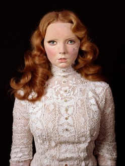 Photograph of model Lily Cole wearing a Victorian lace blouse and a damaged mask of her own face