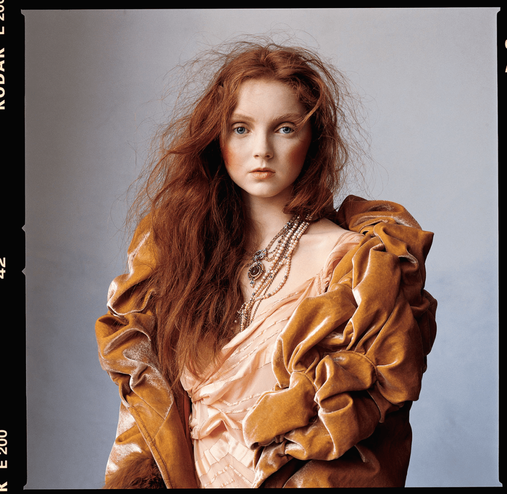 Photograph of model Lily Cole wearing a gold, ruched velvet wrap and her signature red hair teased messily