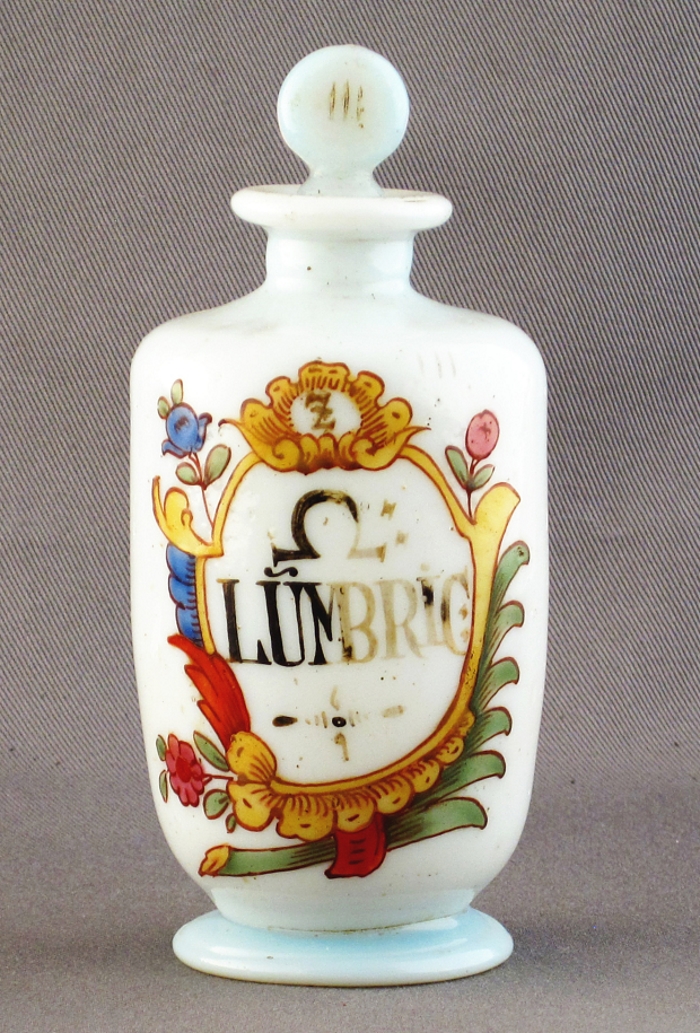 Small white glass apothecary jar with word 'Lumbric' on front and alchemical symbol for spirits